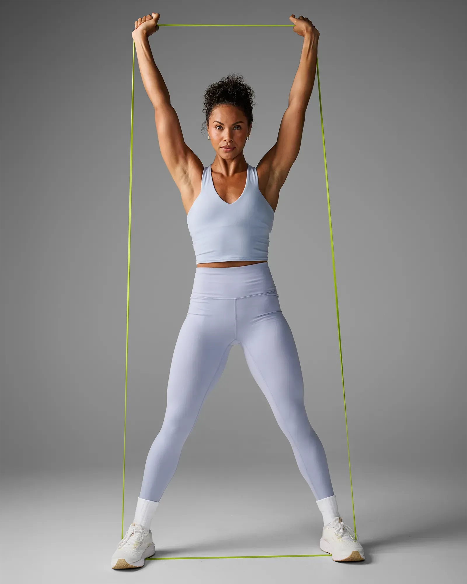 Woman performing a shoulder press using an EQYP yellow elastic super band
