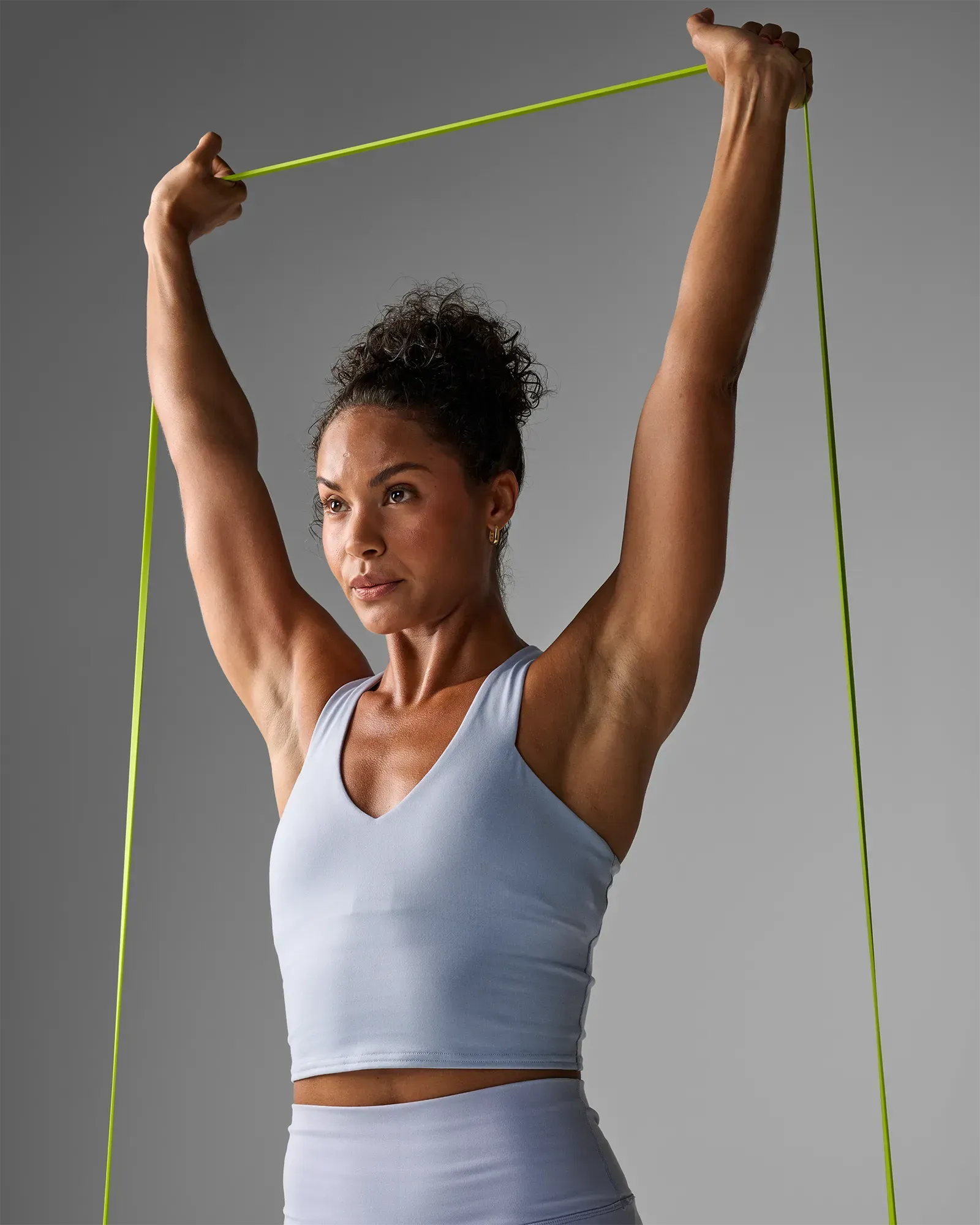 Closeup of woman performing a shoulder press using an EQYP yellow elastic super band