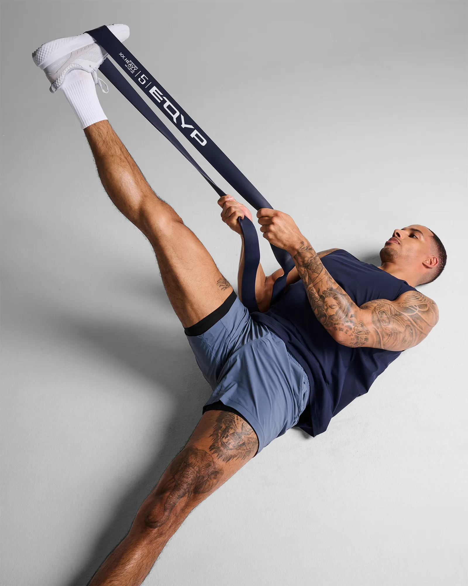 Man performing a lying band-assisted leg raise with EQYP Super Band to stretch the hamstring and improve lower body mobility