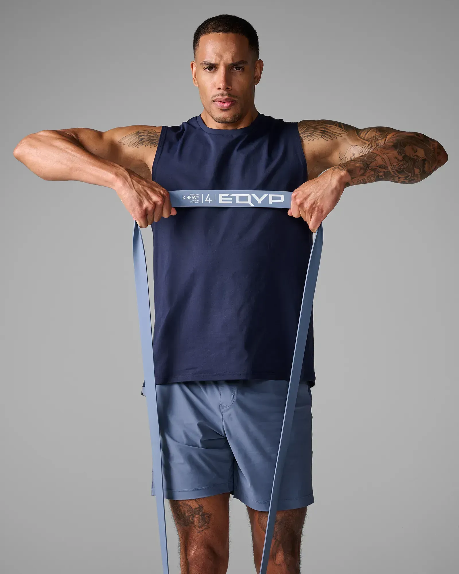 Man performing an upright row using an EQYP light gray elastic wide super band around his feet
