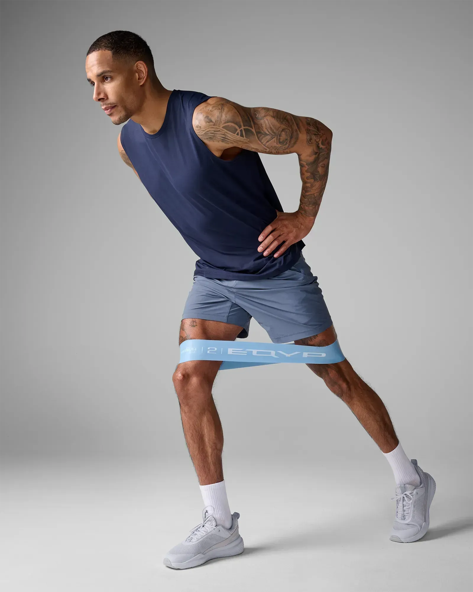 Man performing a standing unilateral lateral band walk using EQYP Ultimate Power Loop Medium light blue resistance band above the knees