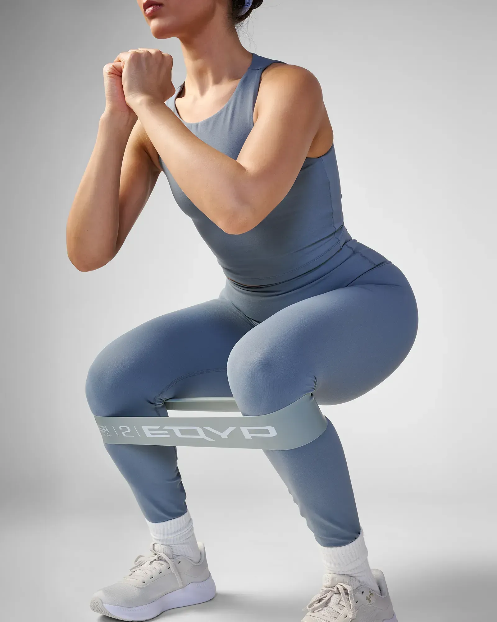 Woman performing a squat using EQYP Advanced Power Loop Medium gray resistance band above the knees
