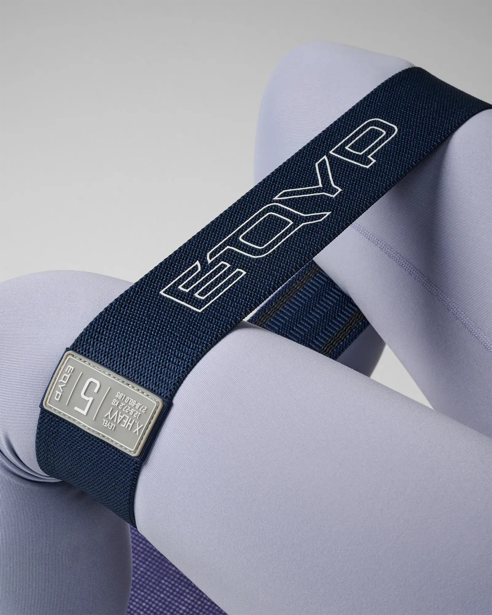 EQYP navy blue elastic wide squat band worn around thighs showing X.Heavy, 12.6–27.2 KG / 27.8–60.0 LBS, Level 5 label detail