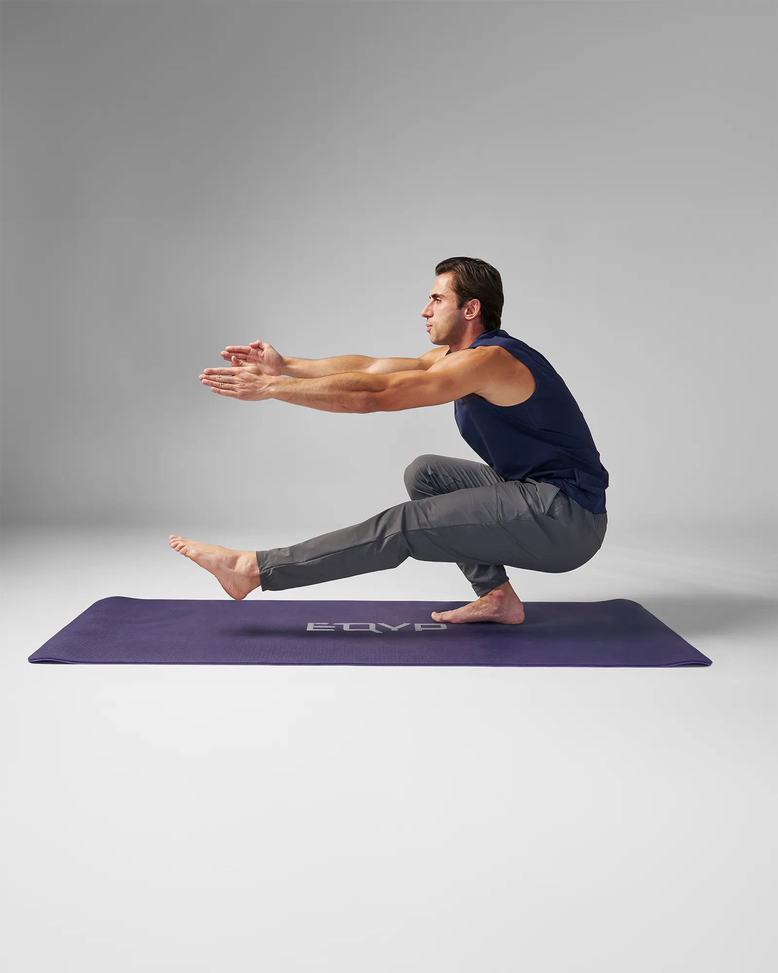 Man performing a unilateral pistol squat on an EQYP Yoga Mat in navy blue
