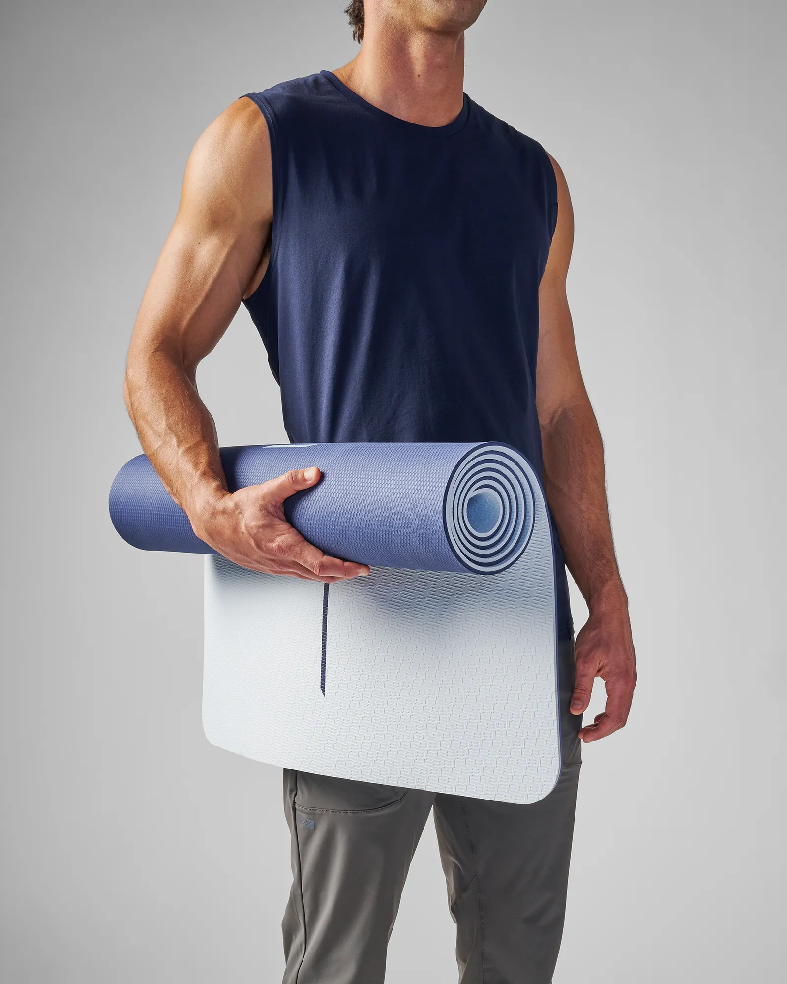 Man standing holding partly rolled up EQYP Dual Layer Yoga Mat