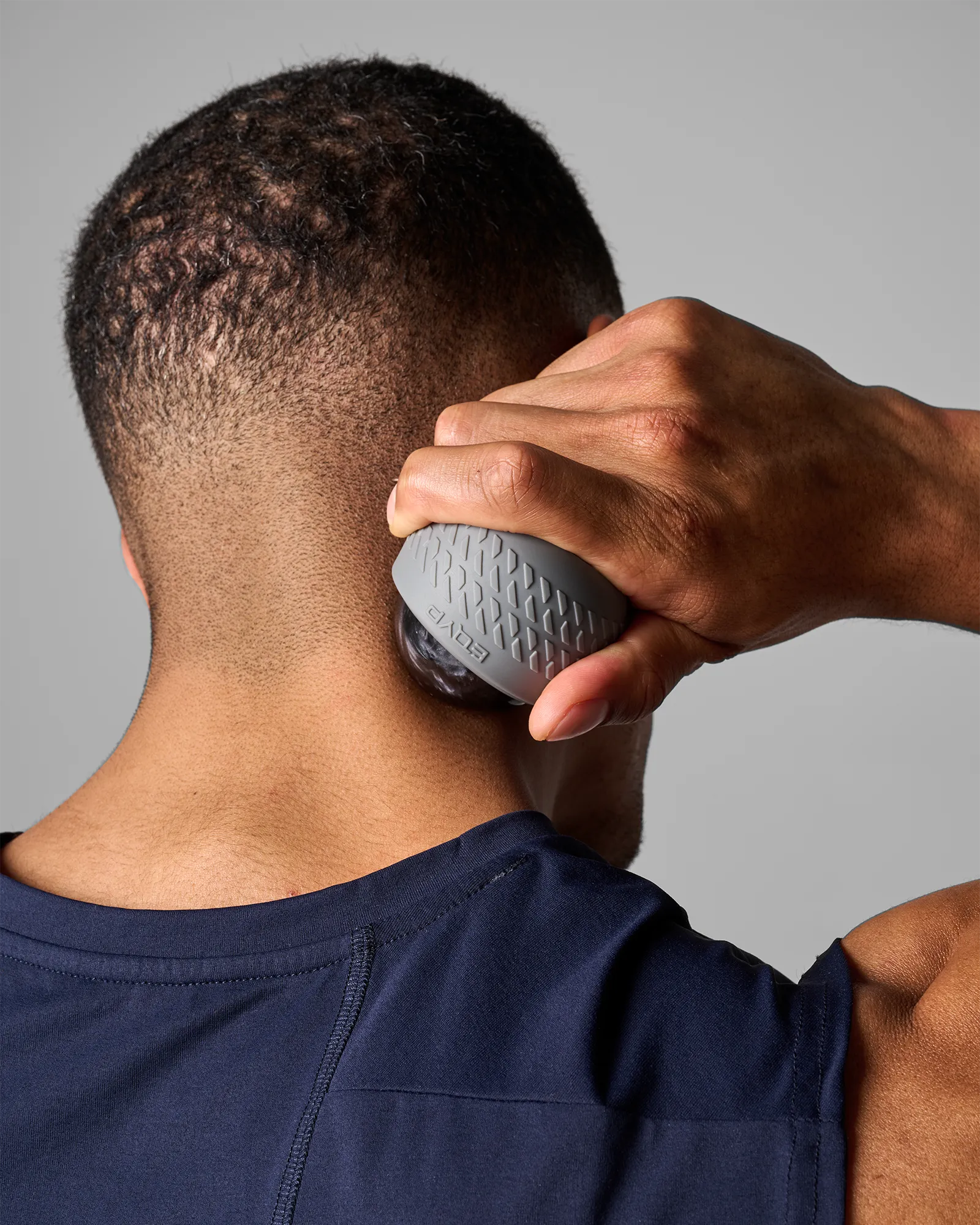 Man using EQYP roll-on massager with textured outer shell on neck