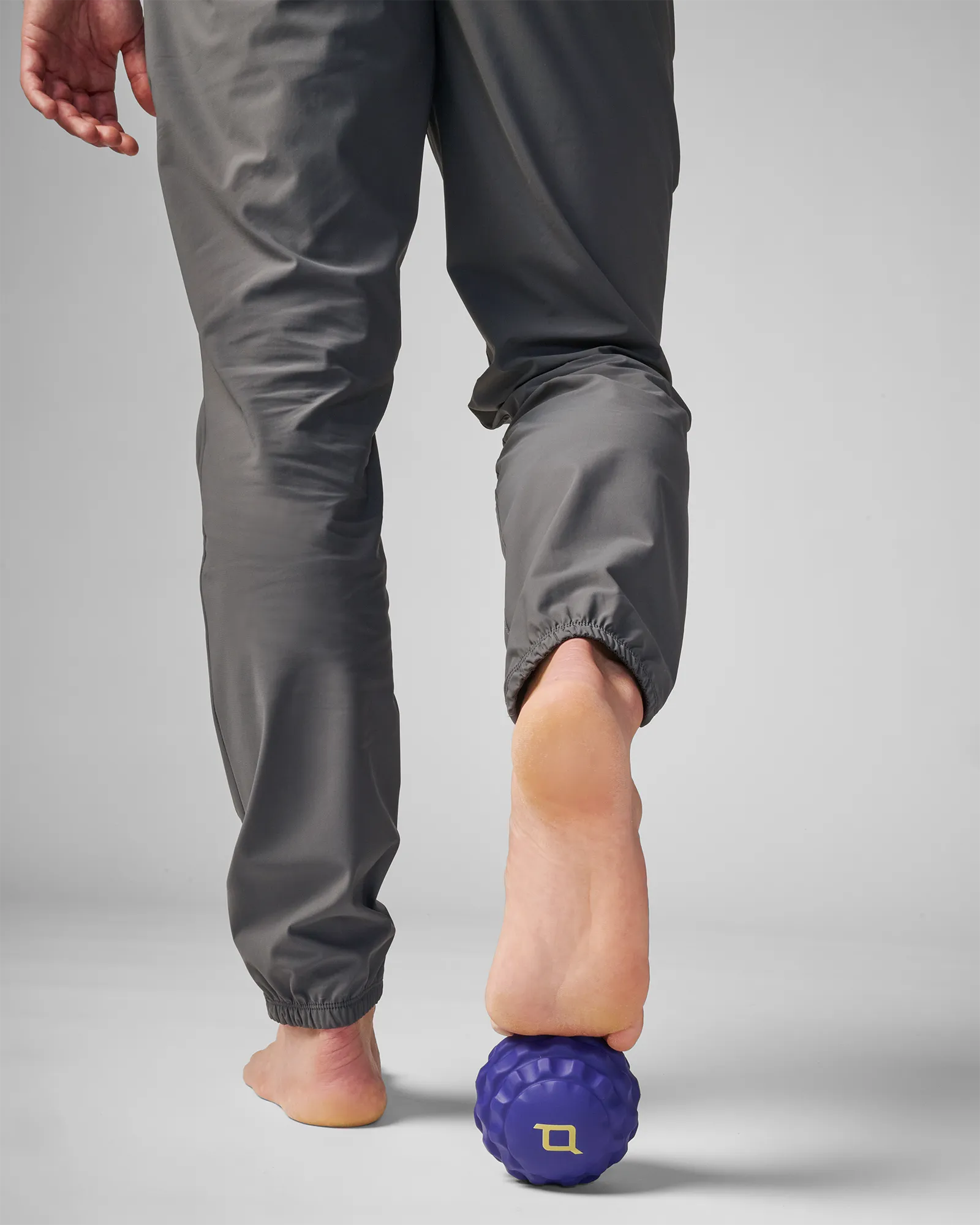 Person rolling medium sized blue EQYP massage ball on front part of foot for muscle relief