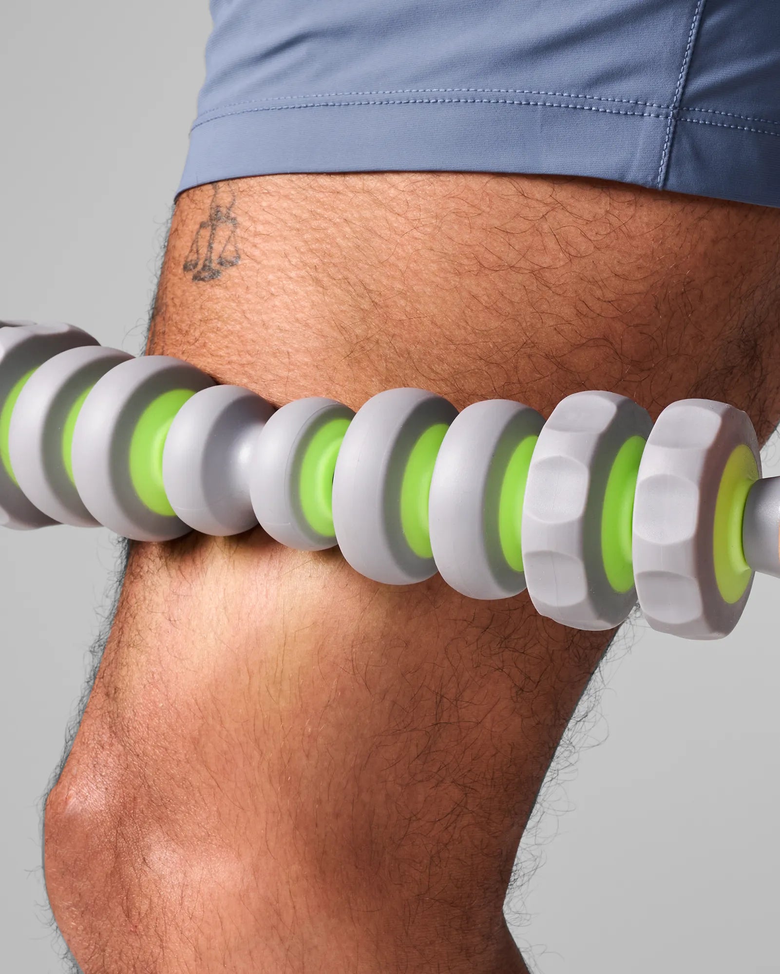 Close up of man using 19 inch EQYP massager bar on upper thigh