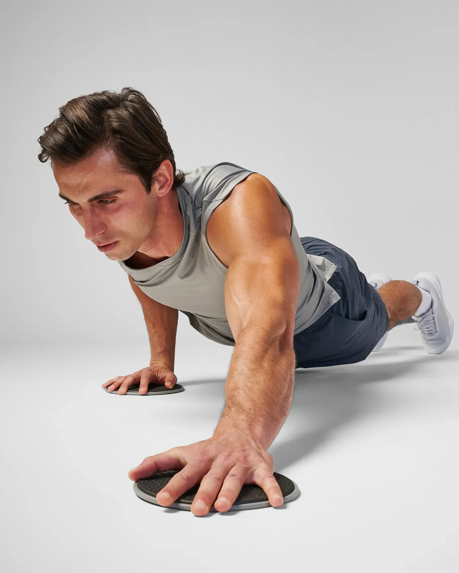 Man performing a sliding bilateral chest fly in a plank position using EQYP Sliding Discs under both hands