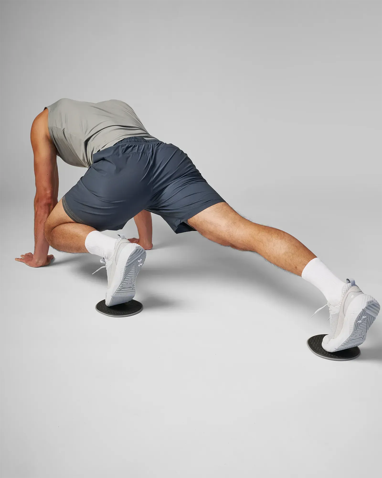 Man performing a sliding unilateral lateral lunge using EQYP Sliding Discs under both feet